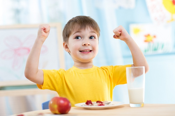 child boy eating healthy food and showing his strength